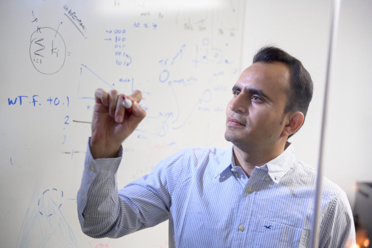 man writing computational solutions on clear board